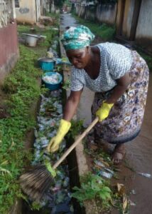 Mama clearing the gutter in front of her house